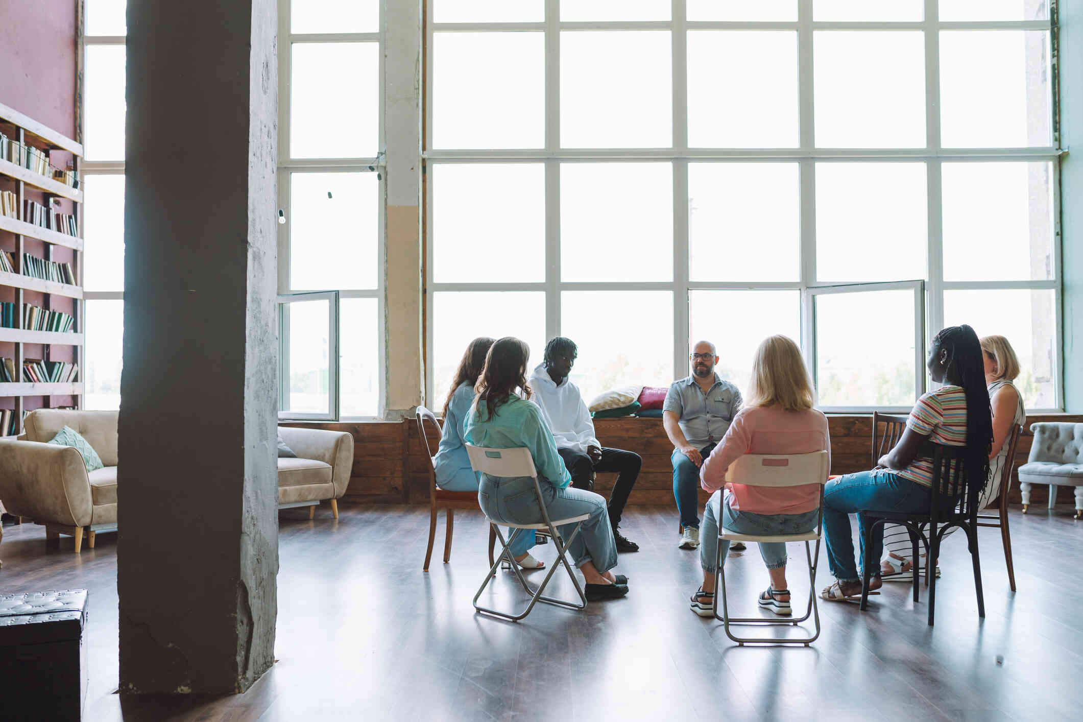 A group of adults sit in chairs in a therapy cirlce.